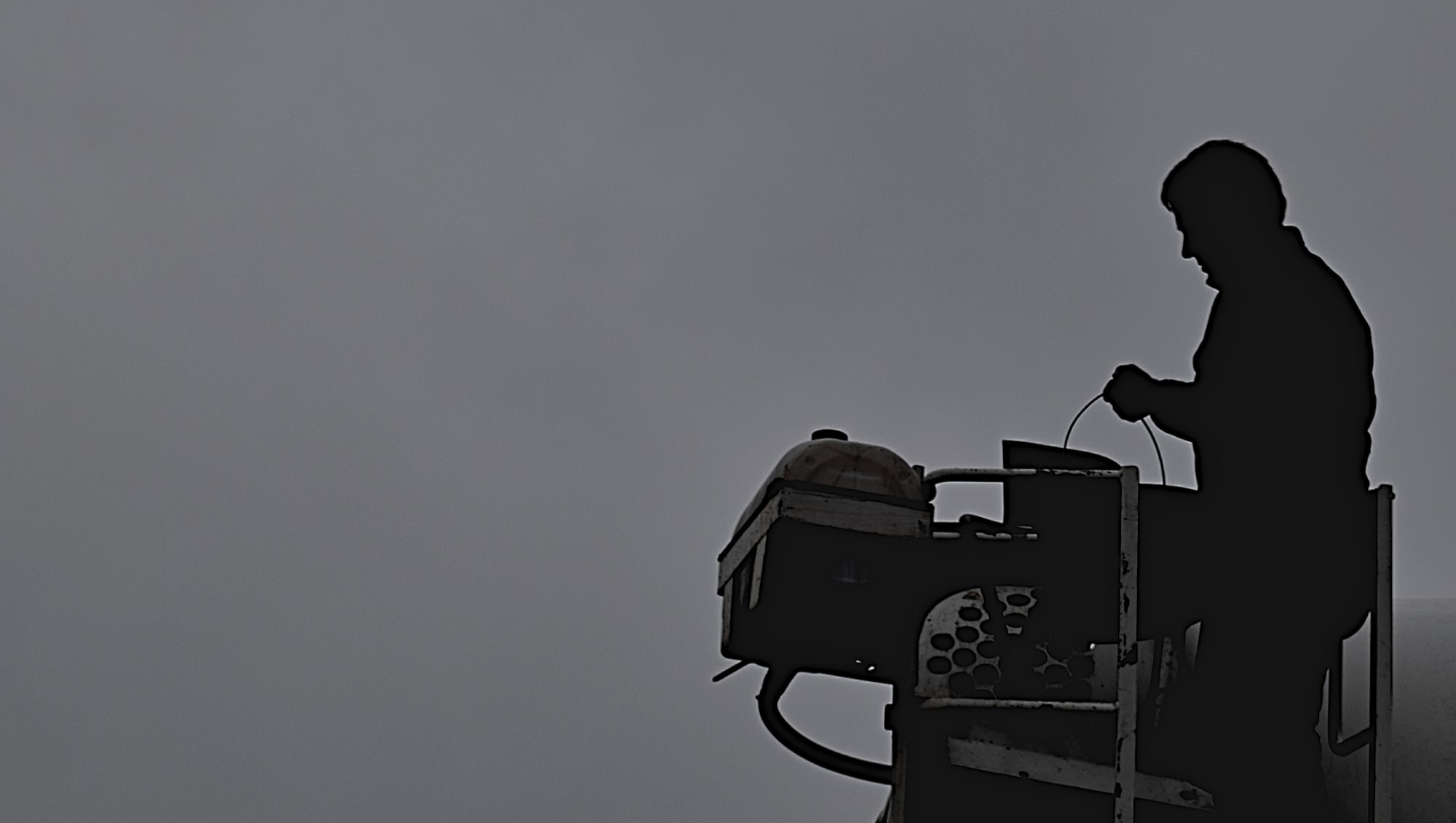 vor grauem Hintergrund ist der Umriss eines Bauarbeiters an einem Betonmischer erkennbar.